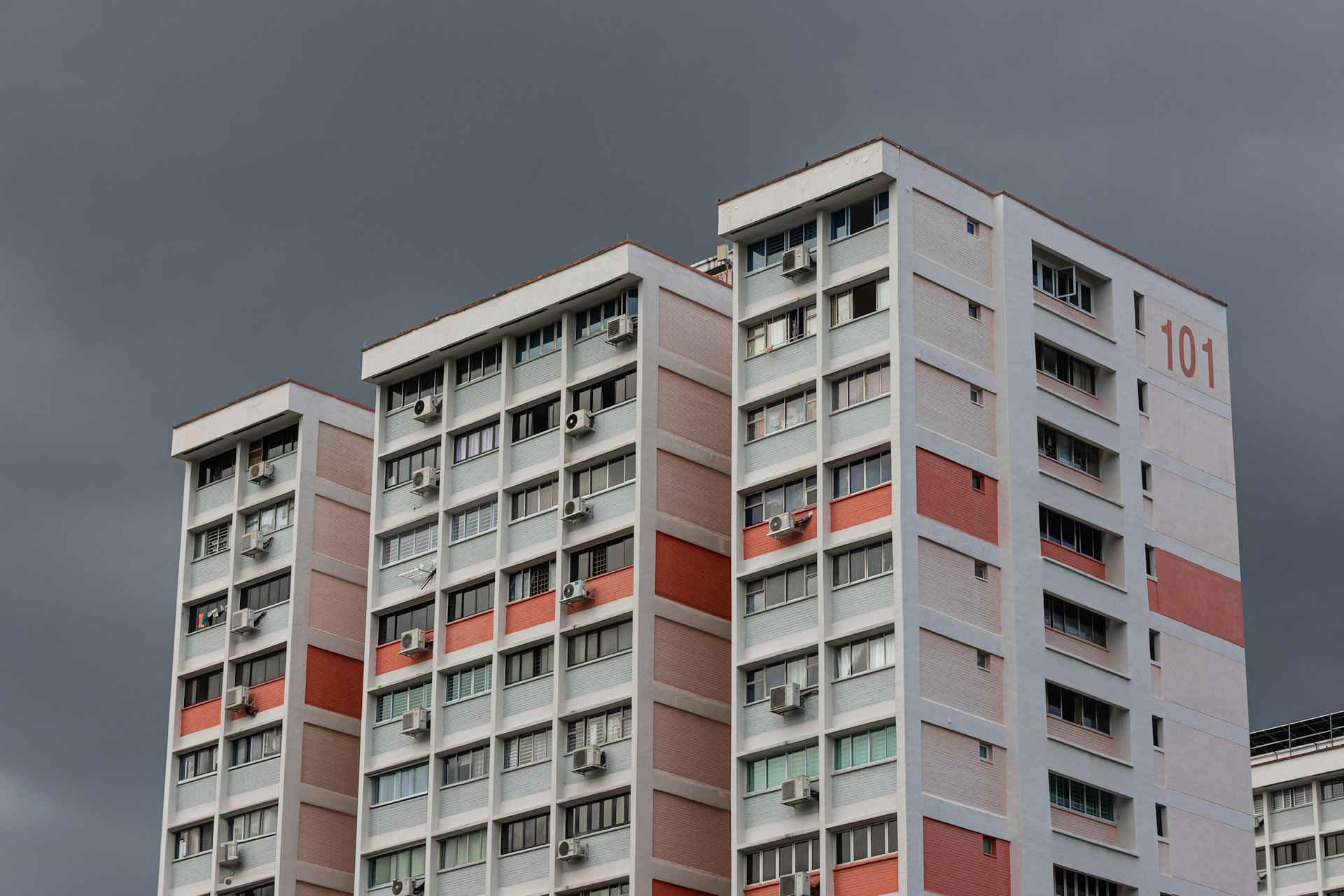 Apartment buildings stand beneath a stormy sky.